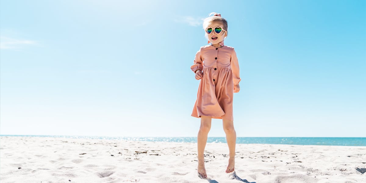 Child on the beach with pink sunglasses loves and wears CANDY children's jewellery