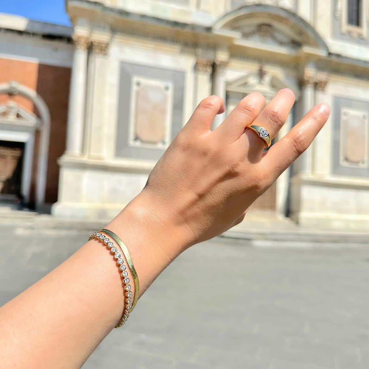 Herringbone-Armband aus vergoldetem Silber getragen mit weiterem Schmuck von CANDY auf einem Piazza in Bellinzona
