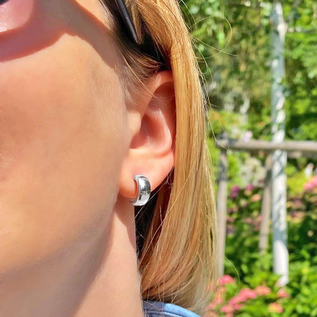 Polierte Ohrringe aus Sterling Silber 925 mit gewölbter Oberfläche in den Schweizer Bergen getragen 
