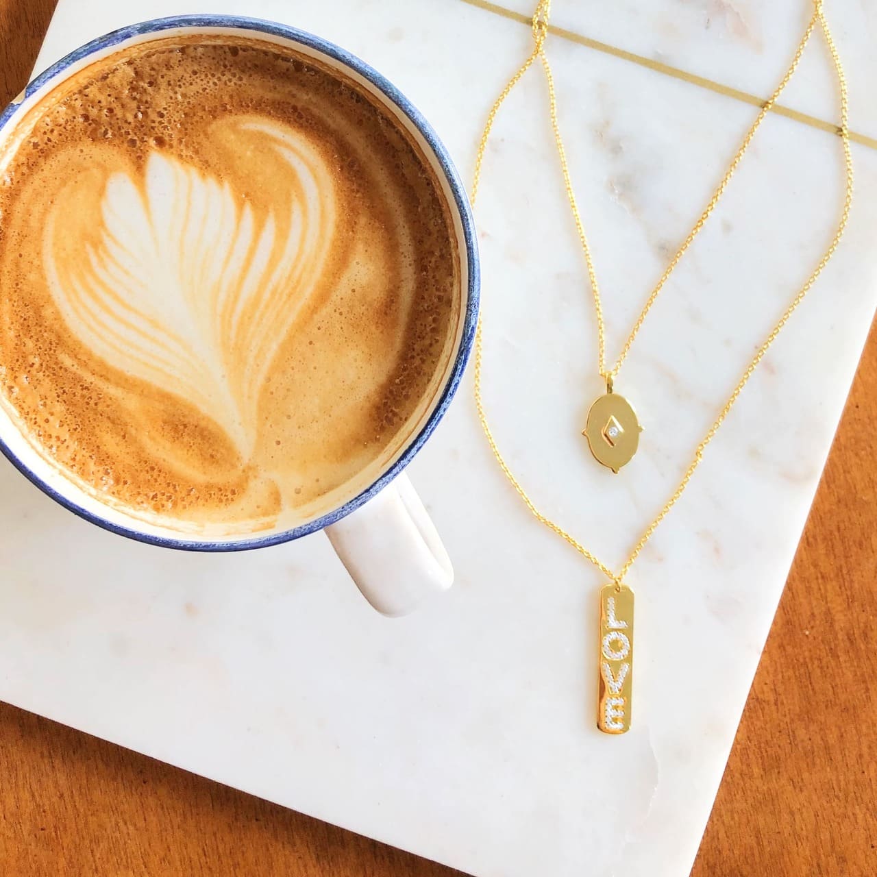Eine Tasse Kaffee und Halsketten aus vergoldetem Silber mit Love-Schriftzug in Café in Basel