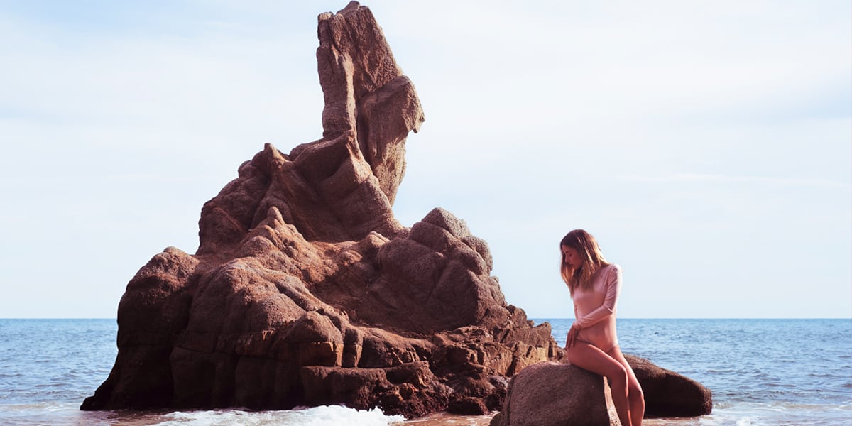 Woman in pink swimming costume on the beach with CANDY jewellery 