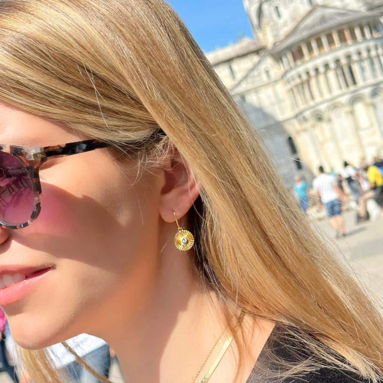 Frau macht mit Ohrhaken aus 18 Karat vergoldetem Silber Sightseeing in der Schweiz
