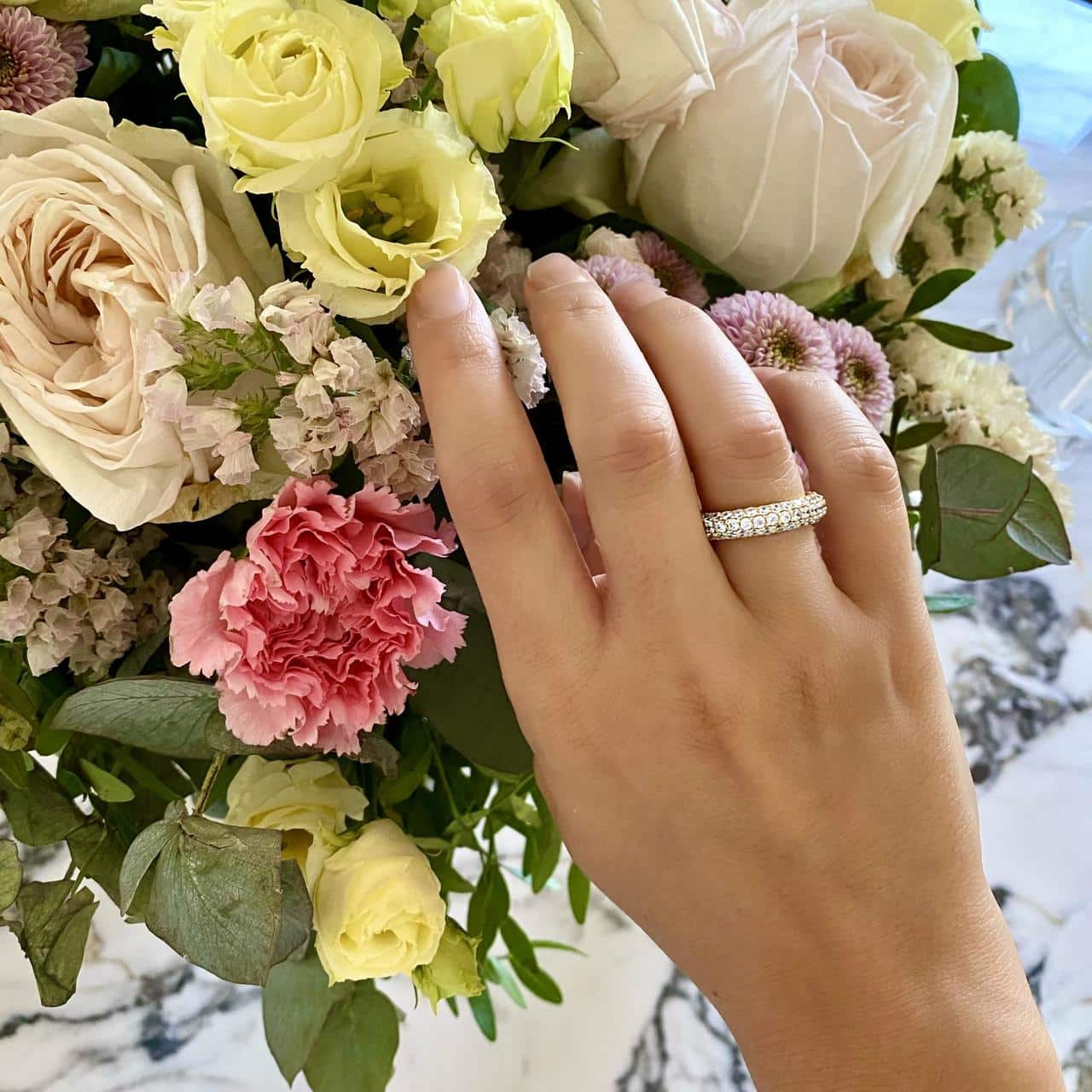 Trägerin eines edlen Pavée-Rings aus vergoldetem Sterling Silber wir mit Blumen in Davos überrascht 