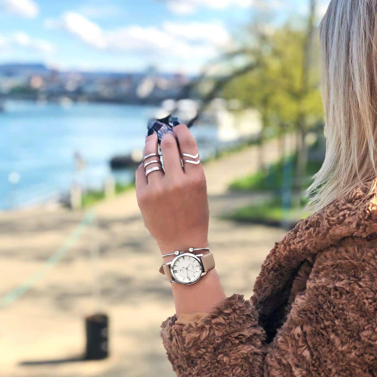 Model trägt Silberarmreif , Silberringe und eine Armbanduhr und  blickt auf den Rhein in Basel