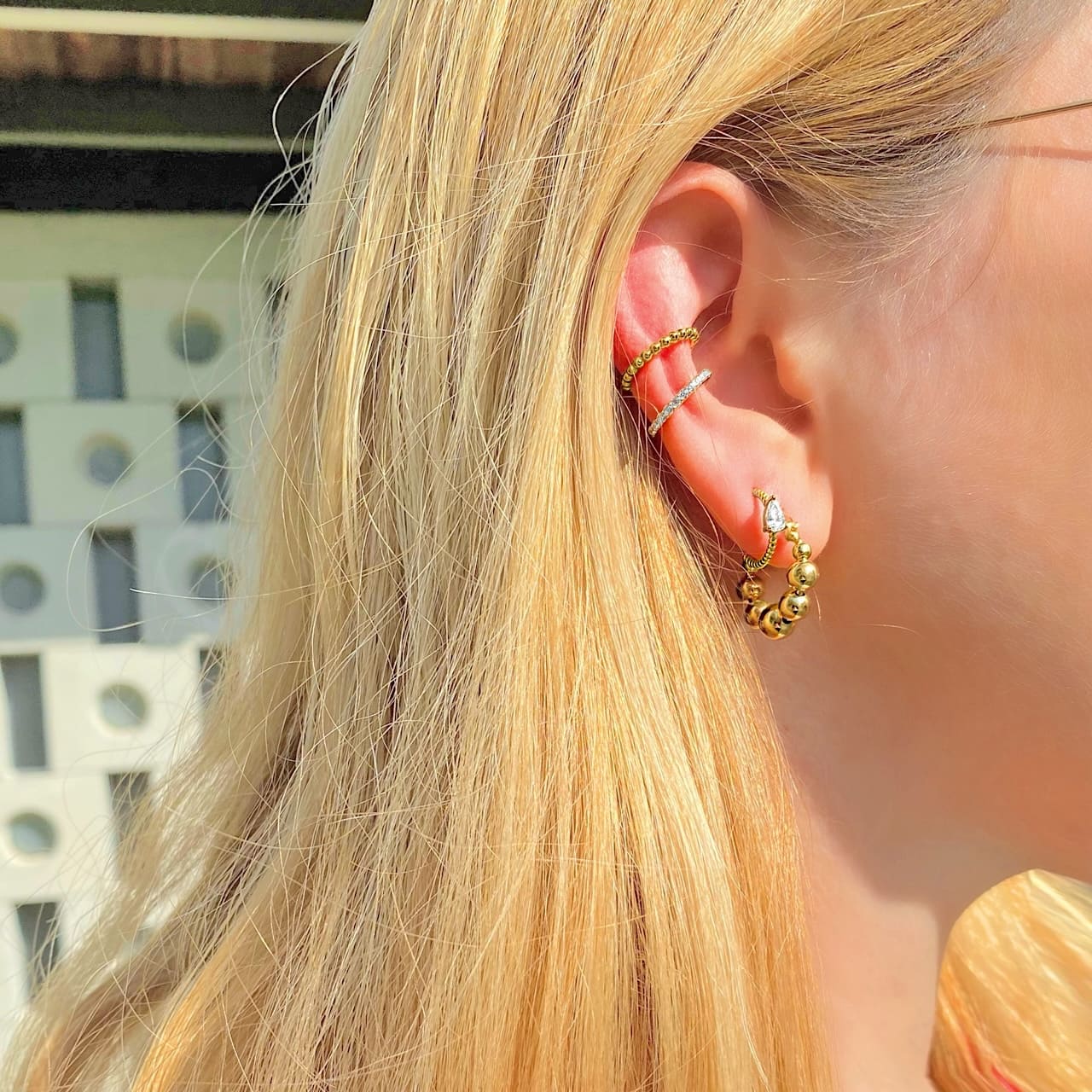 Model trägt angesagten Ear Stack mit mehreren Creolen und Ear Cuffs aus 18 Karat vergoldetem Sterling Silber in Solothurn